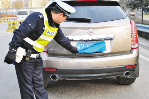 民警正在对一辆故意遮挡车牌的汽车进行查处