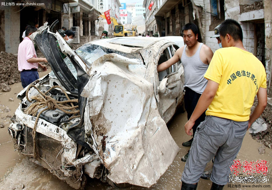 8月18日，甘肃舟曲泥石流灾区，一辆挖掘机将一辆被泥石流冲毁的小轿车从废墟中推了出来，让前来认领的车主将车拉走。