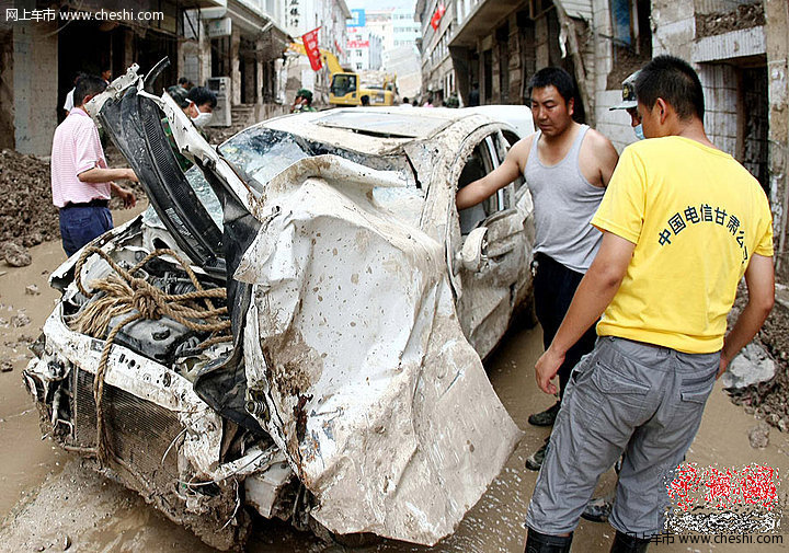 8月18日，甘肃舟曲泥石流灾区，一辆挖掘机将一辆被泥石流冲毁的小轿车从废墟中推了出来，让前来认领的车主将车拉走。