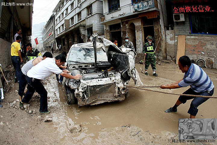 8月18日，甘肃舟曲泥石流灾区，一辆挖掘机将一辆被泥石流冲毁的小轿车从废墟中推了出来，让前来认领的车主将车拉走。